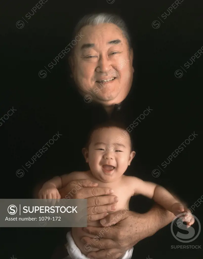 Portrait of a senior man holding his grandson and smiling