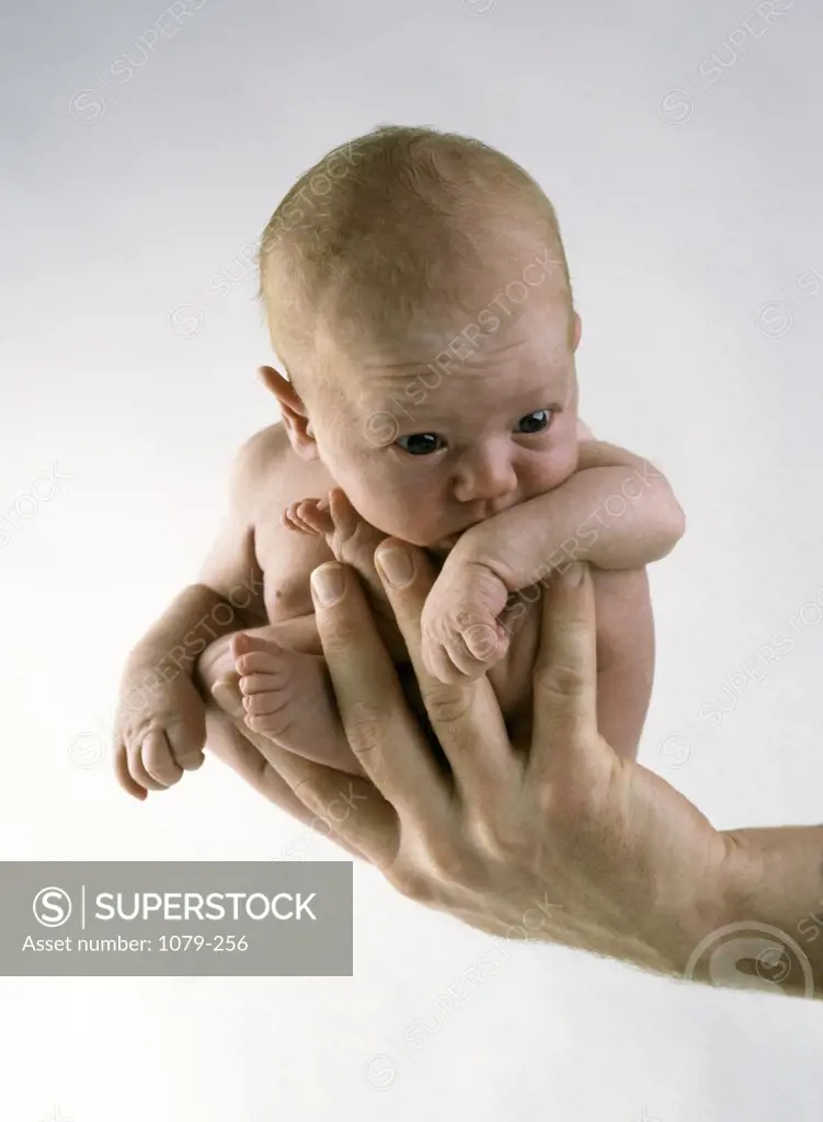 Close-up of a human hand holding a newborn baby