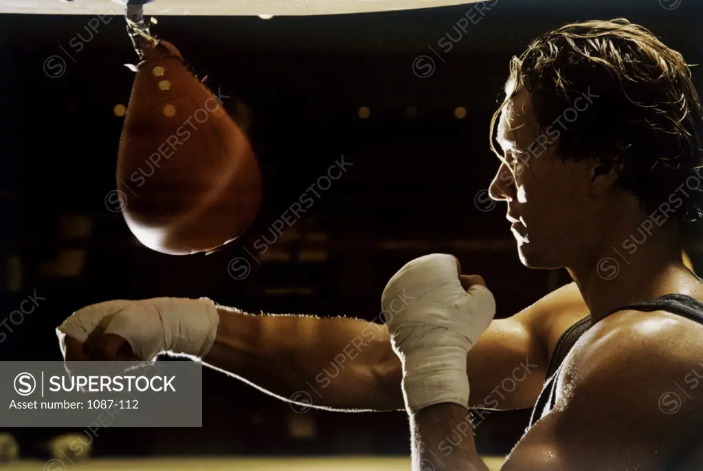 Side profile of a young man punching a punching bag