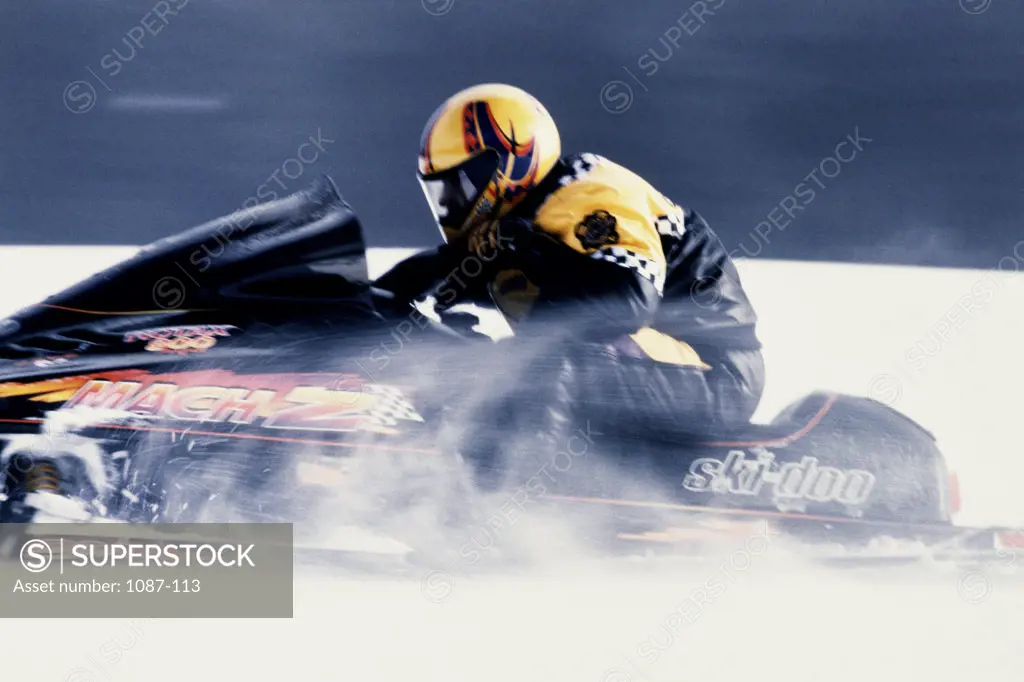 Side profile of a person riding a snowmobile