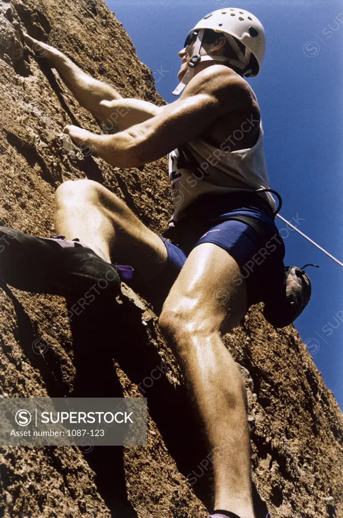 Low angle view of a young man climbing a mountain