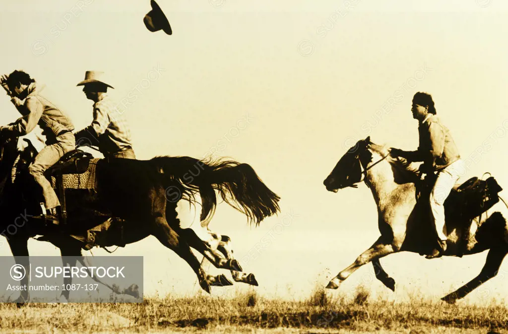 Side profile of three cowboys riding horses