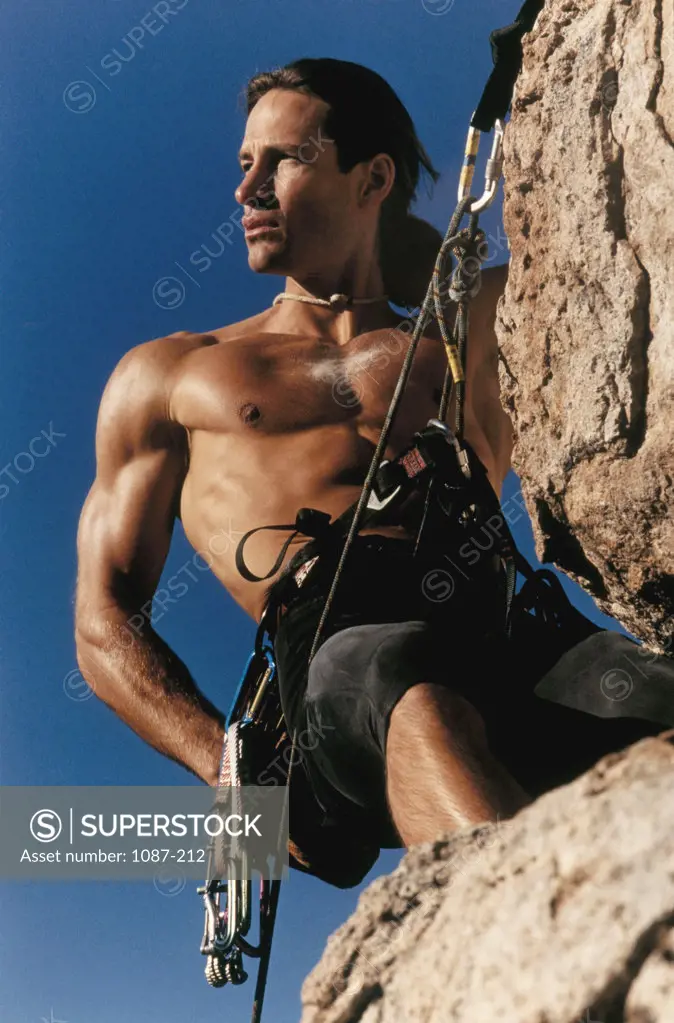 Low angle view of a young man climbing a mountain