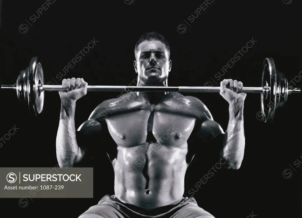 Portrait of a young man exercising with a barbell