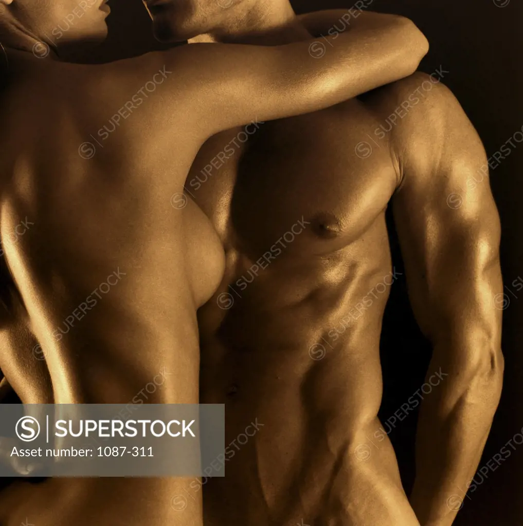 Mid section view of a naked young couple embracing each other