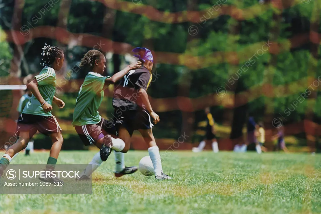 Side profile of three girls playing soccer