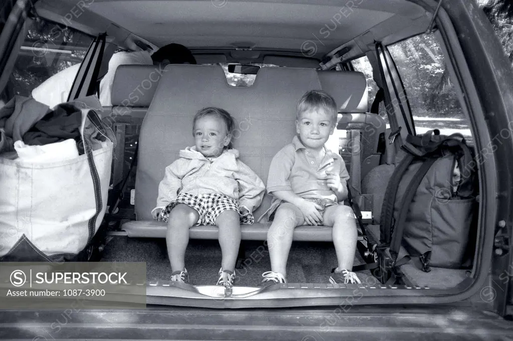 Boy and a girl sitting in a car trunk