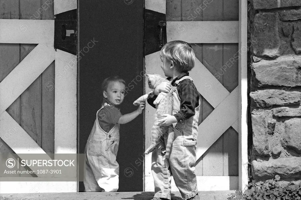 Girl looking at her brother holding a cat