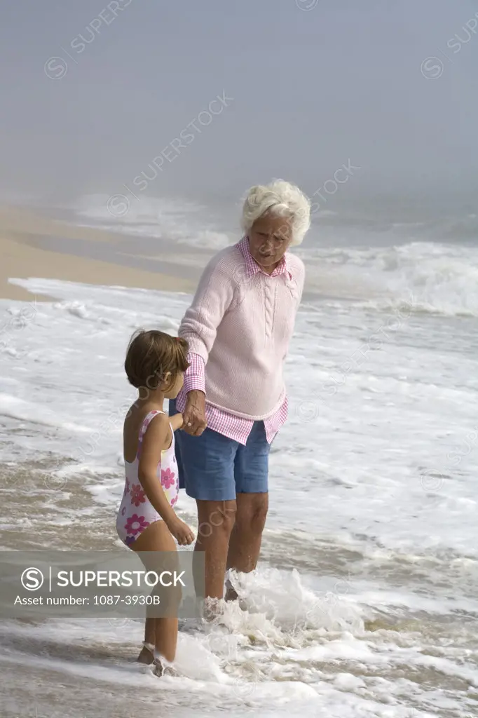 Girl standing on the beach with her grandmother