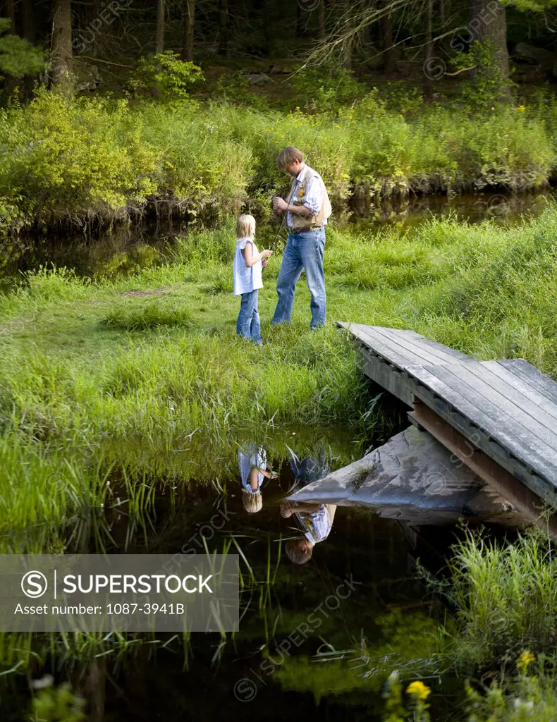 Man and his daughter fishing in a creek