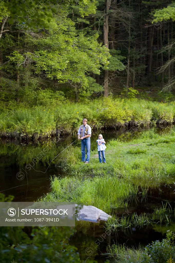 Man and his daughter fishing in a creek