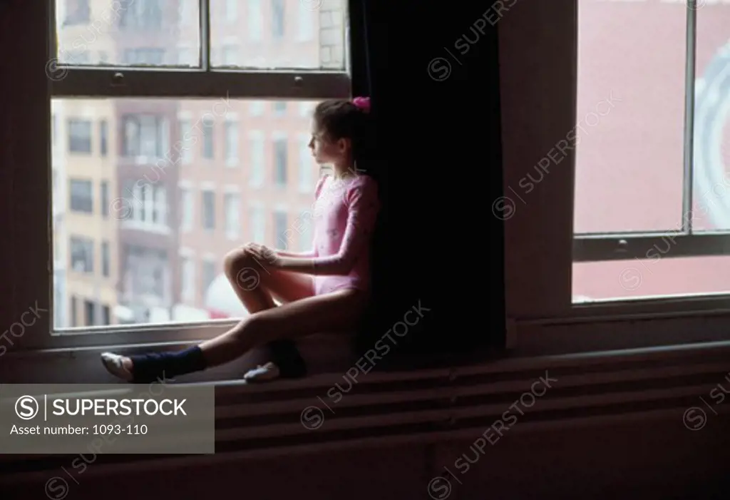 Side profile of a ballerina looking through a window
