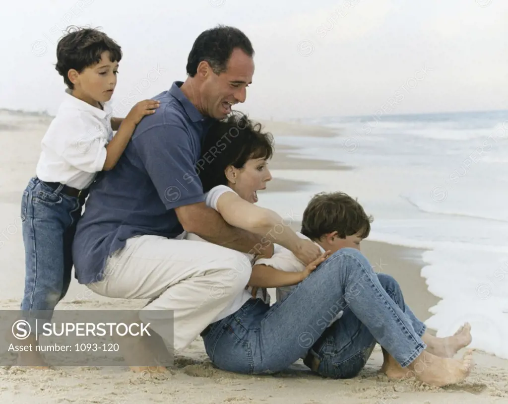 Side profile of parents with their two sons on the beach