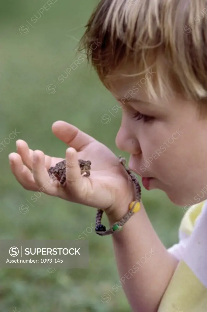 Side profile of a boy holding a frog in his hand