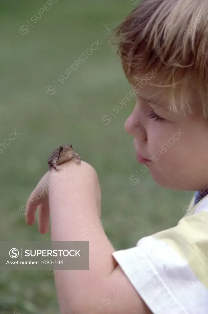 Side profile of a boy with a frog on his hand