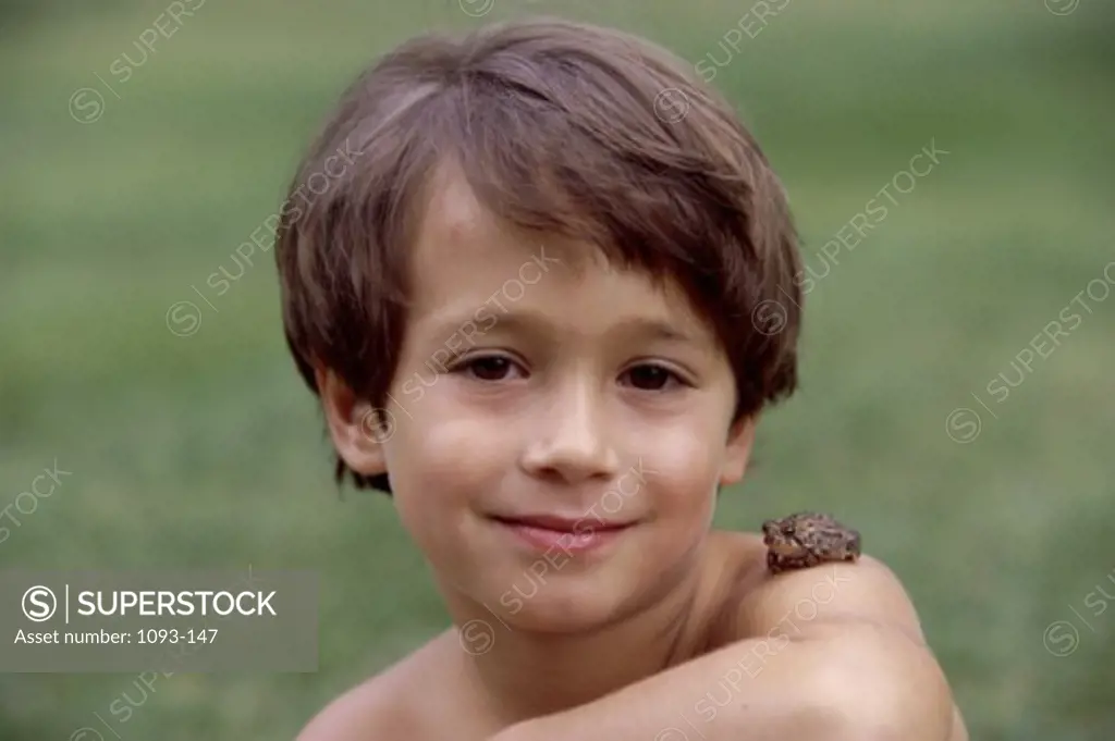 Portrait of a boy smiling with a frog on his shoulder