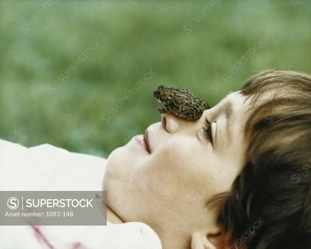 Side profile of a boy with a frog on his face