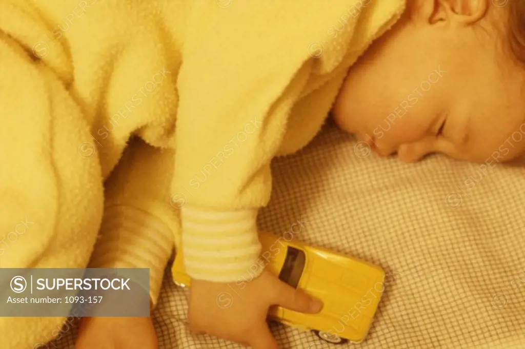High angle view of a baby boy sleeping with a toy car
