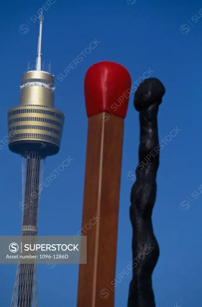 Low angle view of two matchstick sculptures with a tower, Amp Tower, Sydney, New South Wales, Australia
