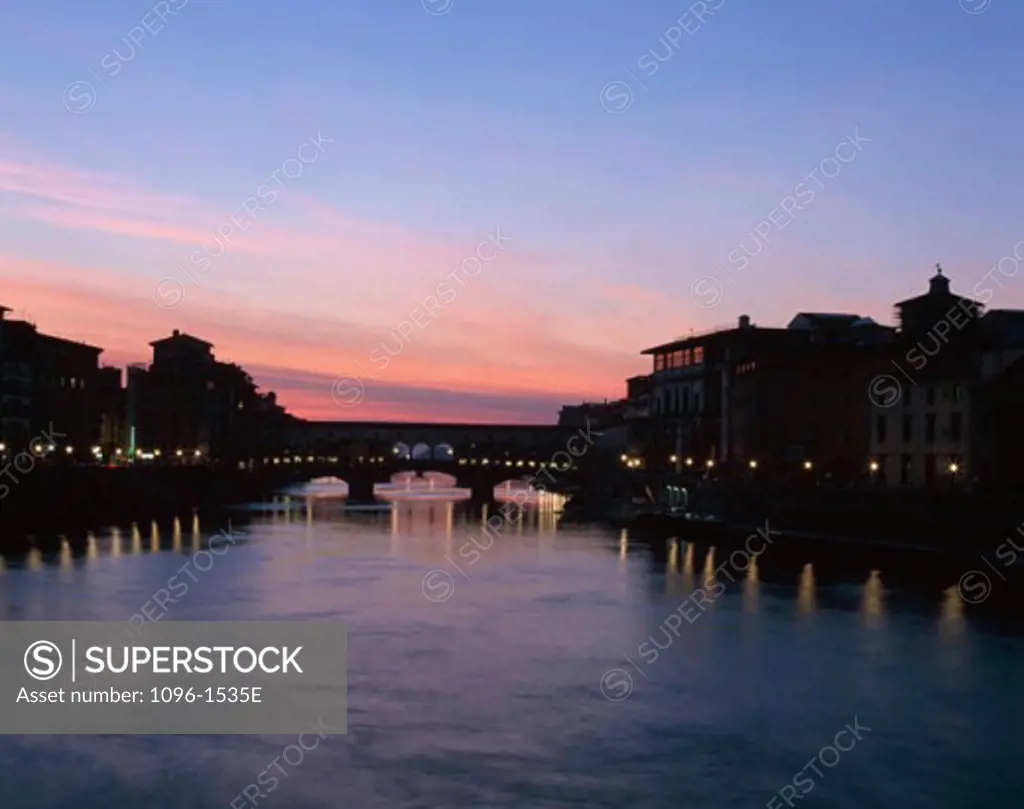 Silhouette of a bridge across a river lit up at dusk, Ponte Vecchio, Florence, Italy