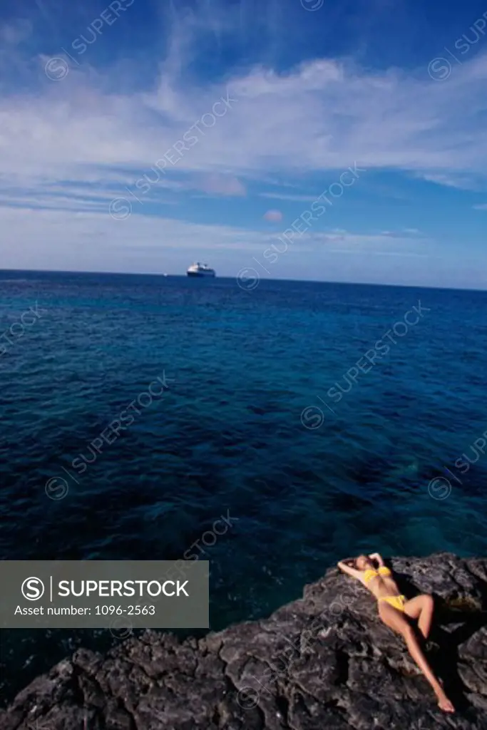 Young woman sunbathing on a rock, Great Shrimp Cay, Bahamas