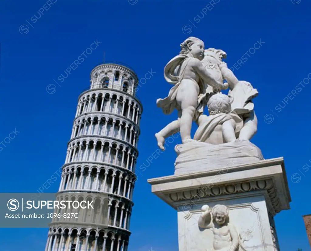 Low angle view of a statue with the Leaning Tower of Pisa in the background, Italy