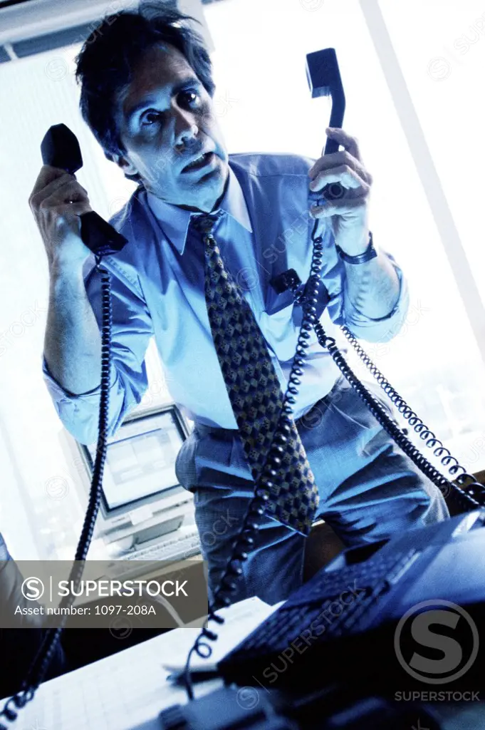 Businessman holding two telephone receivers