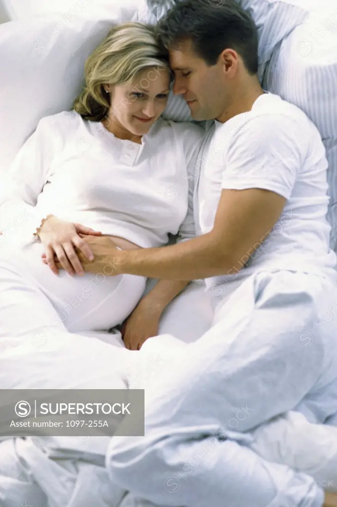 Husband lying in bed with his pregnant wife