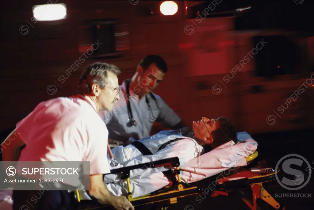 Two paramedics pushing a man on a stretcher