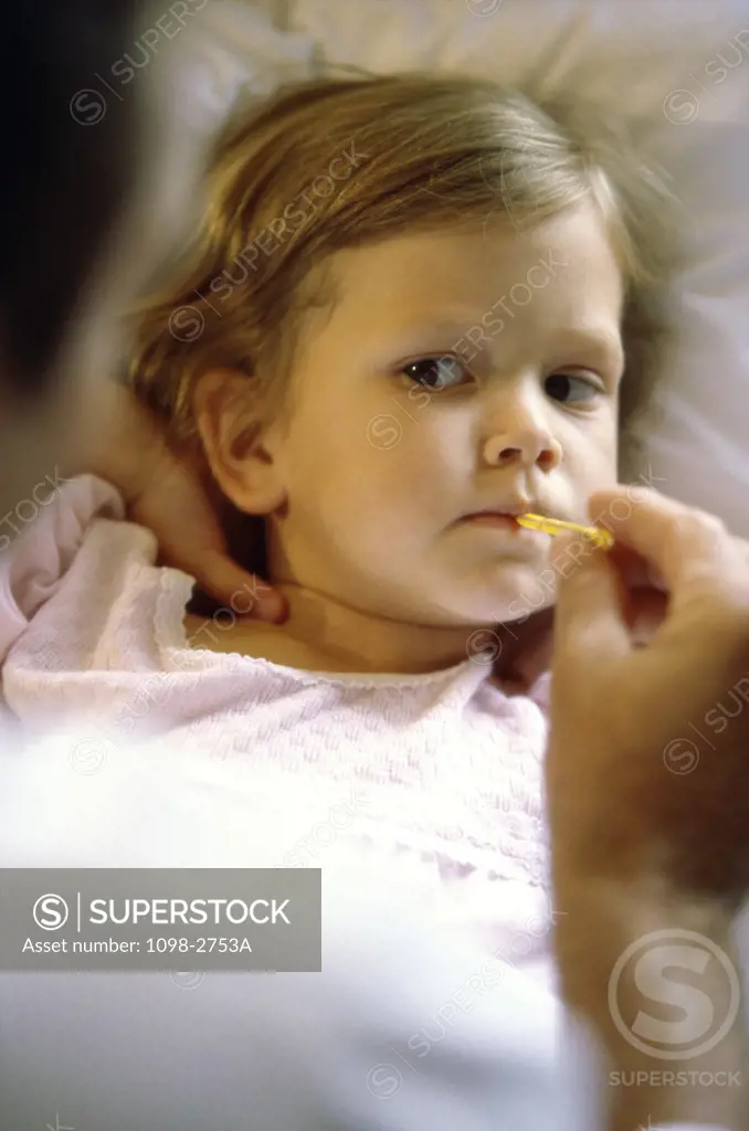 High angle view of a thermometer in a girl's mouth