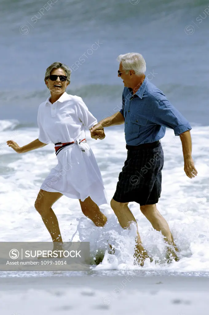 Senior couple wading in water on the beach