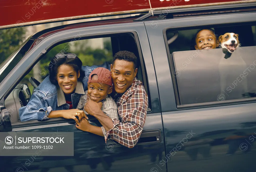 Portrait of parents sitting in a car with their children