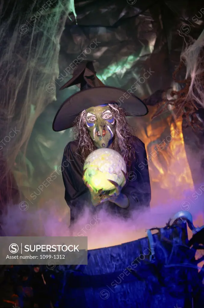 Witch holding a crystal ball standing in front of a cauldron
