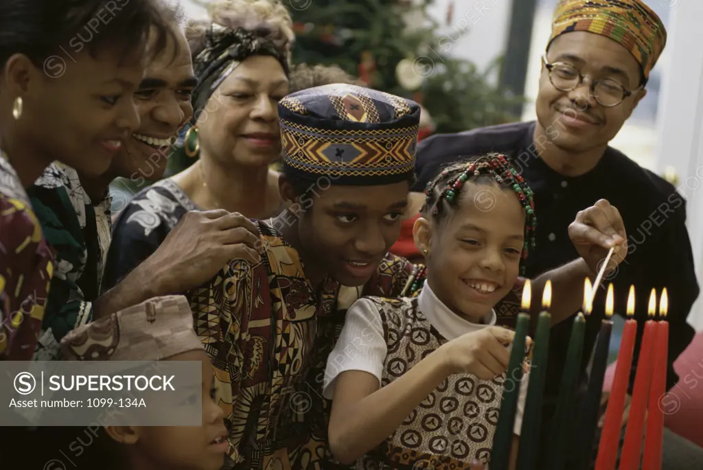 Family standing behind a lit Mishumaa Saba to celebrate Kwanzaa