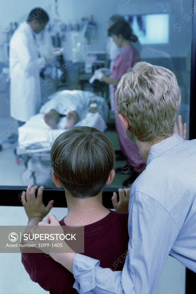 Rear view of mid adult woman standing with her son looking into an emergency room