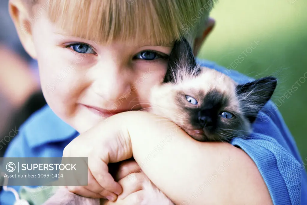 Portrait of a boy holding a Siamese kitten