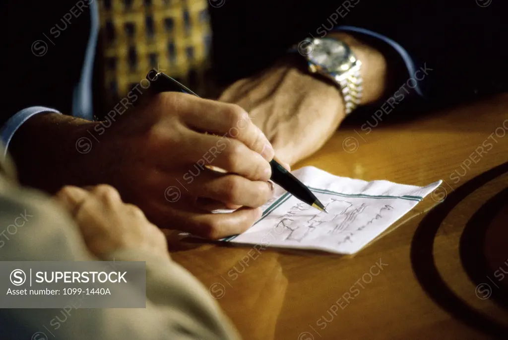 Close-up of a businessman writing on paper