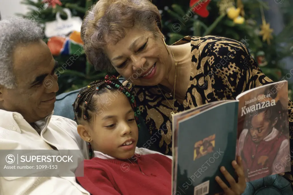 Grandparents reading a book to their granddaughter