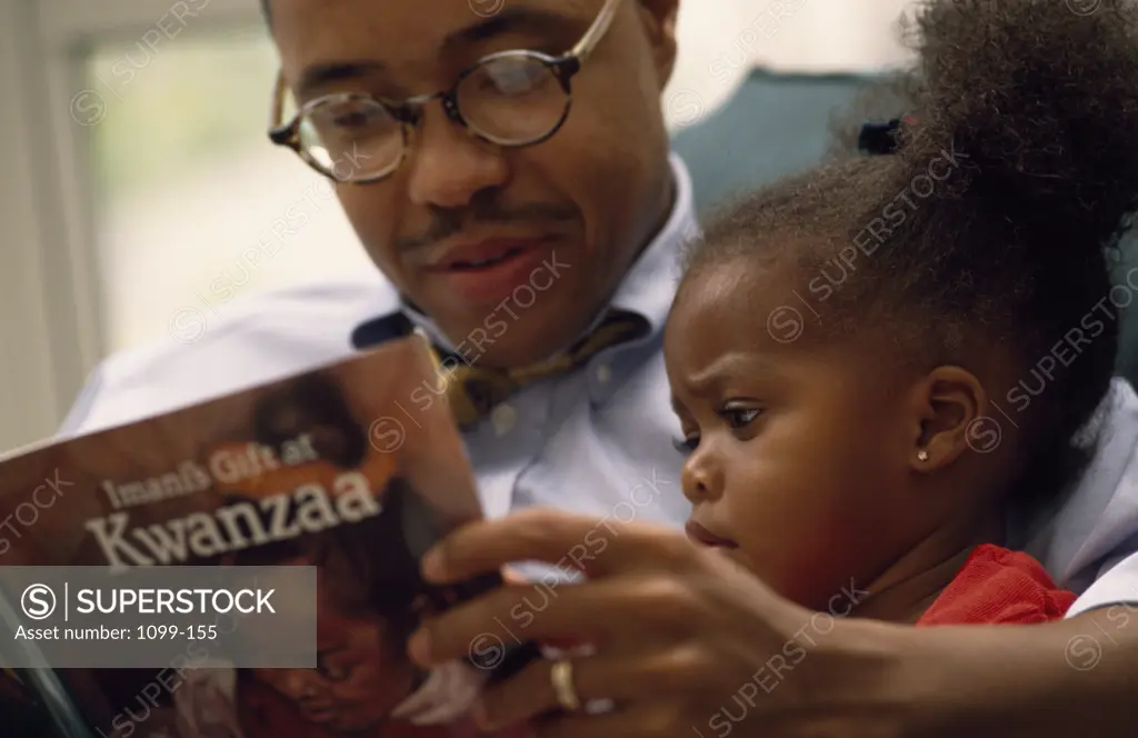 Close up of father and daughter reading book