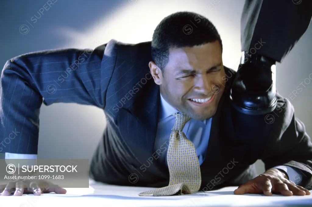 Businessman pushed down by a person's foot
