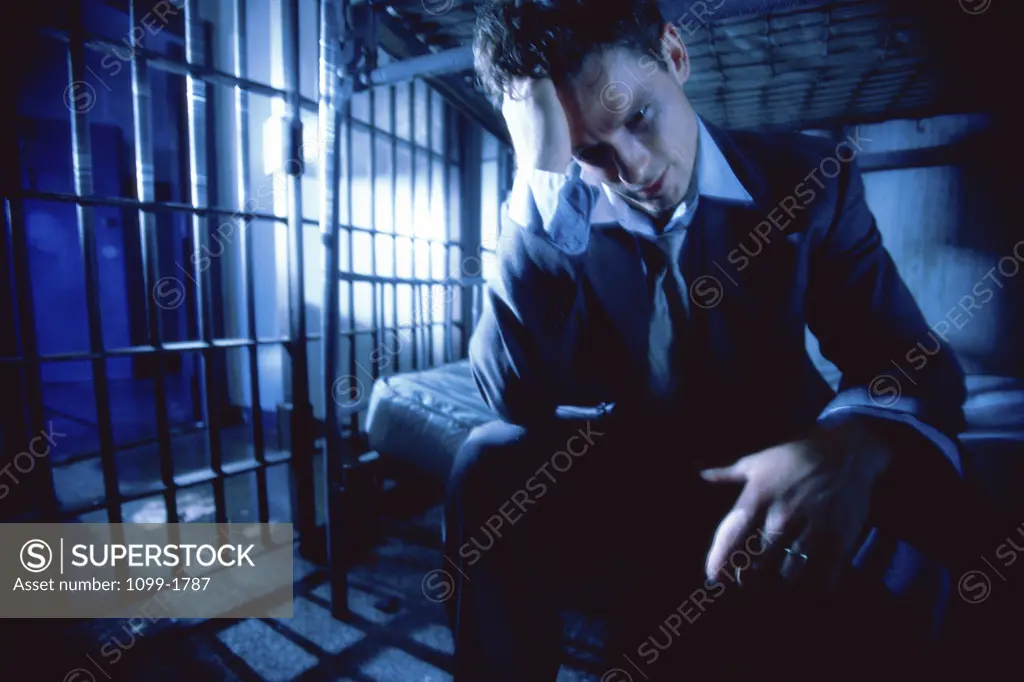 Businessman sitting in a prison cell