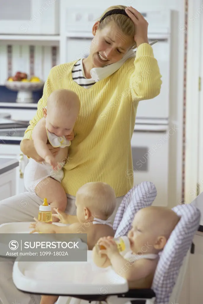 Mother with her three baby boys talking on a cordless phone