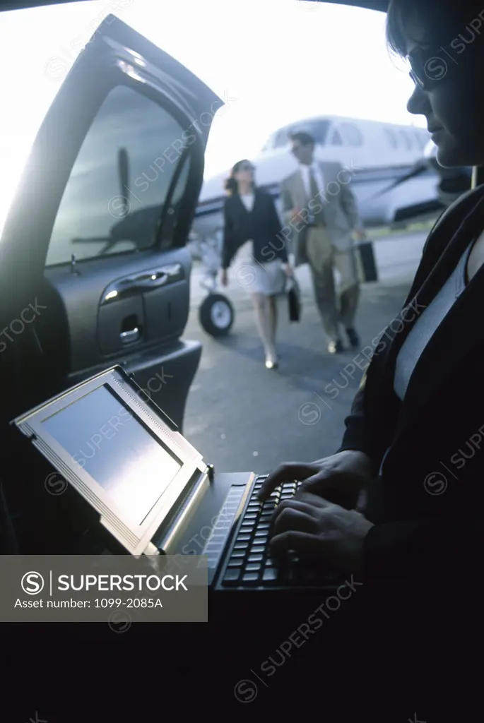 Businesswoman working on a laptop in a car