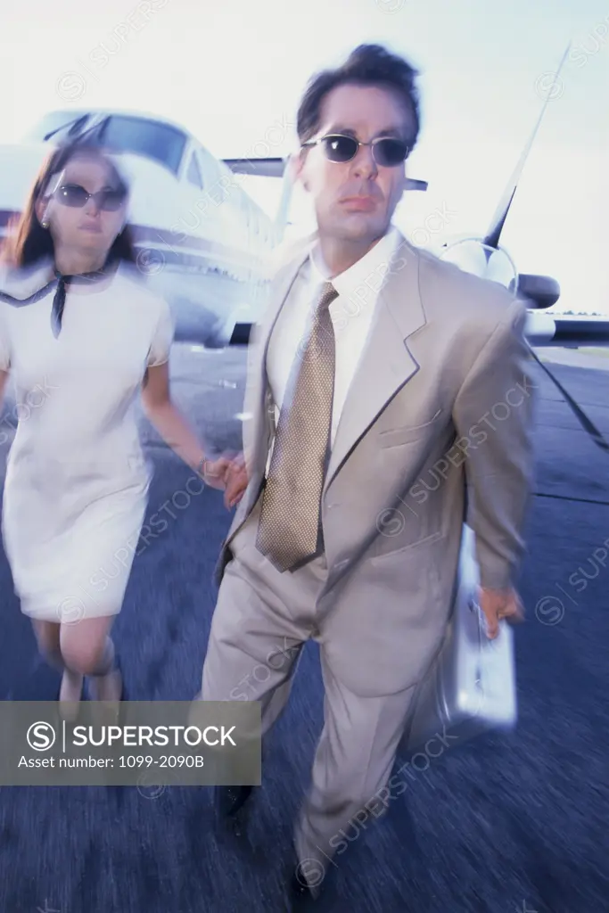Businessman and a businesswoman running at an airport