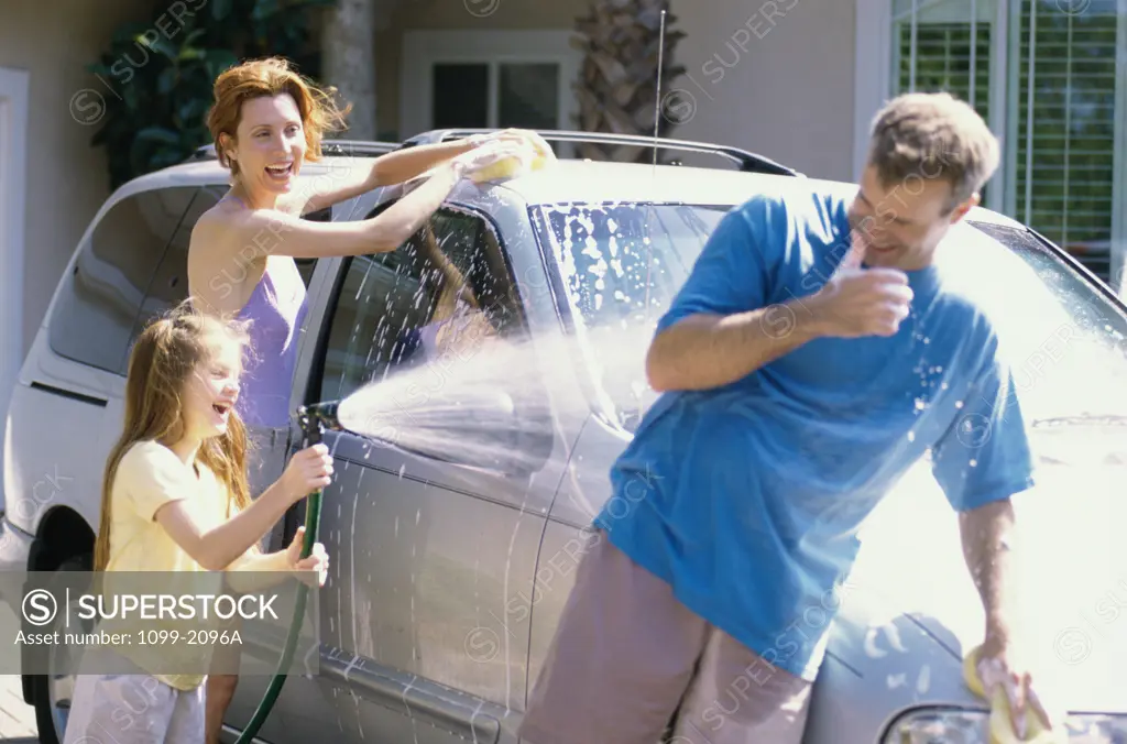 Daughter and her parents washing a car