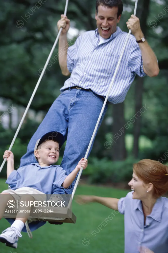 Father standing on a swing with his son