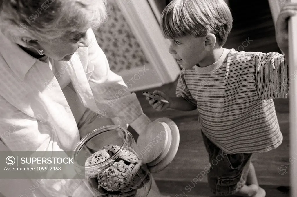 Grandmother holding a cookie jar in front of her grandson