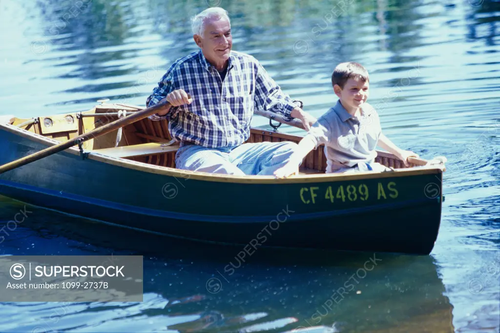 Grandfather and his grandson in a row boat on the river
