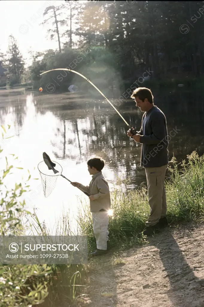 Mid adult man fishing with his son at a lakeside
