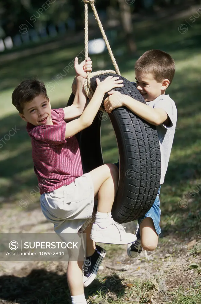 Two boys climbing a tire swing